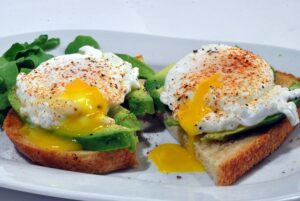 breakfast meal of avacado toast with poached eggs and greens